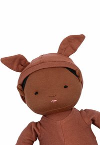 Une poupée en tissu marron avec de longues oreilles, des traits du visage simples et un corps texturé. La tenue s'harmonise avec le teint de la peau dans un design doux et minimal.