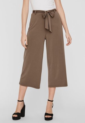 Pantalons larges marron avec une taille ceinturée, en tissu texturé et d'une longueur raccourcie, associés à des sandales à plateforme noires.