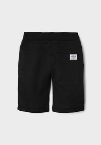 Black cotton shorts with a waistband, featuring a single back pocket and rolled hems, displaying a logo tag on the back.