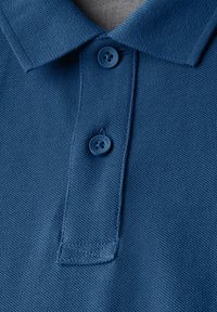 Mörkblå pikétröja gjord av texturerad tyg med krage, som har två matchande knappar och en liten sidosprunddetalj.