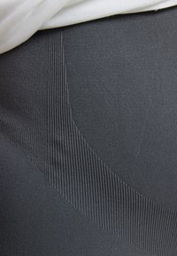 Black leggings with a textured, ribbed design and smooth areas, featuring a form-fitting shape and a soft, stretchy fabric.