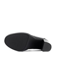 Suola di scarpa nera con tacco alto, dotata di una presa testurizzata, area della punta liscia e forma leggermente curvata. Realizzata in materiale di gomma resistente.