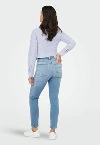 Heledsinine teksapüksid slim-fit lõikega, vahepealse vöökoha, tagataskute ja tagasihoidlike õmblusdetailidega. Koos triibulise särgiga.