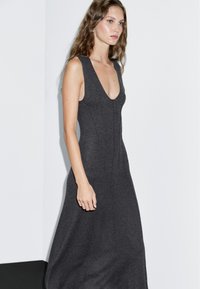 Robe sans manches gris charbon avec un décolleté en V profond, corsage ajusté et coutures verticales, créant une silhouette élancée.