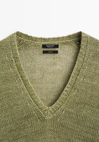 Lichtgroen linnen trui met V-hals, voorzien van een gestructureerd breipatroon en labels met de merknaam "Massimo Dutti" en materiaalspecificaties.