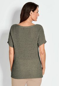 Olivegrünes Strickoberteil mit kurzen Ärmeln, das ein strukturiertes, geripptes Muster und einen weiten, runden Ausschnitt aufweist. Rückansicht.