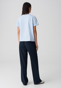 Lichtblauwe katoenen t-shirt met korte, omgeslagen mouwen, gecombineerd met donkerblauwe, losse broek met een gladde textuur en een ontspannen ontwerp.