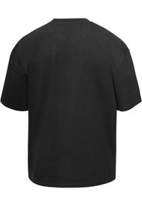 Camiseta de algodón negra con un corte holgado, mangas cortas y un escote redondo. Diseño sencillo sin patrones ni marcas visibles.