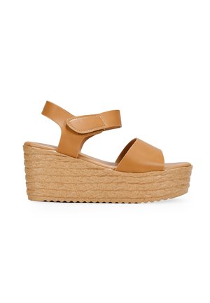 Sandales compensées en cuir tan avec une semelle en liège texturée, un design ouvert à l'avant et une sangle ajustable à la cheville. Silhouette simple et moderne.