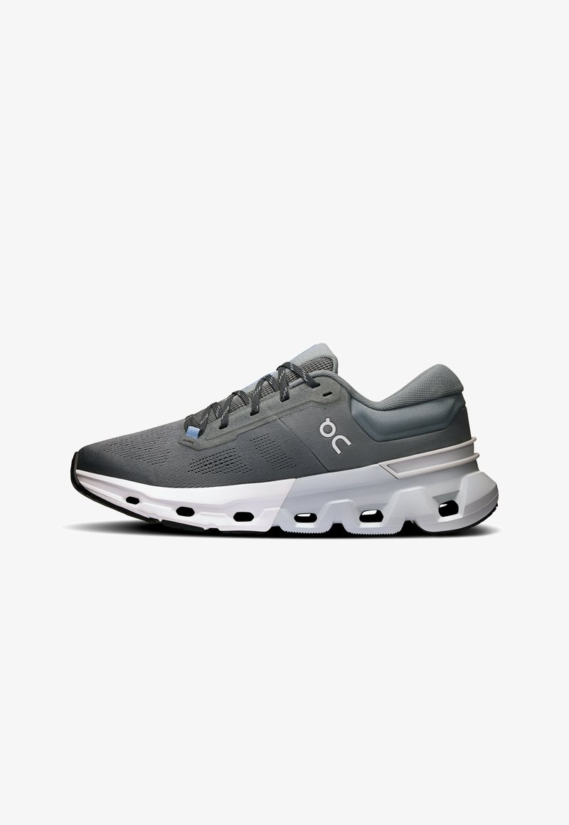 Gray athletic shoe with mesh upper, textured detailing, padded collar, white midsole, and rubber outsole with cutouts for flexibility.
