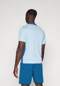 Manskjorta med kort ärm i ljusblått med mörkblå detaljer, tillverkad av ett mjukt och lätt tyg. Har en klassisk krage och avslappnad passform.