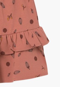 Roze katoenen rok met een gerimpelde zoom, versierd met een patroon van eikels en stippen in bruin en oranje. Glad materiaal met gestikte details.