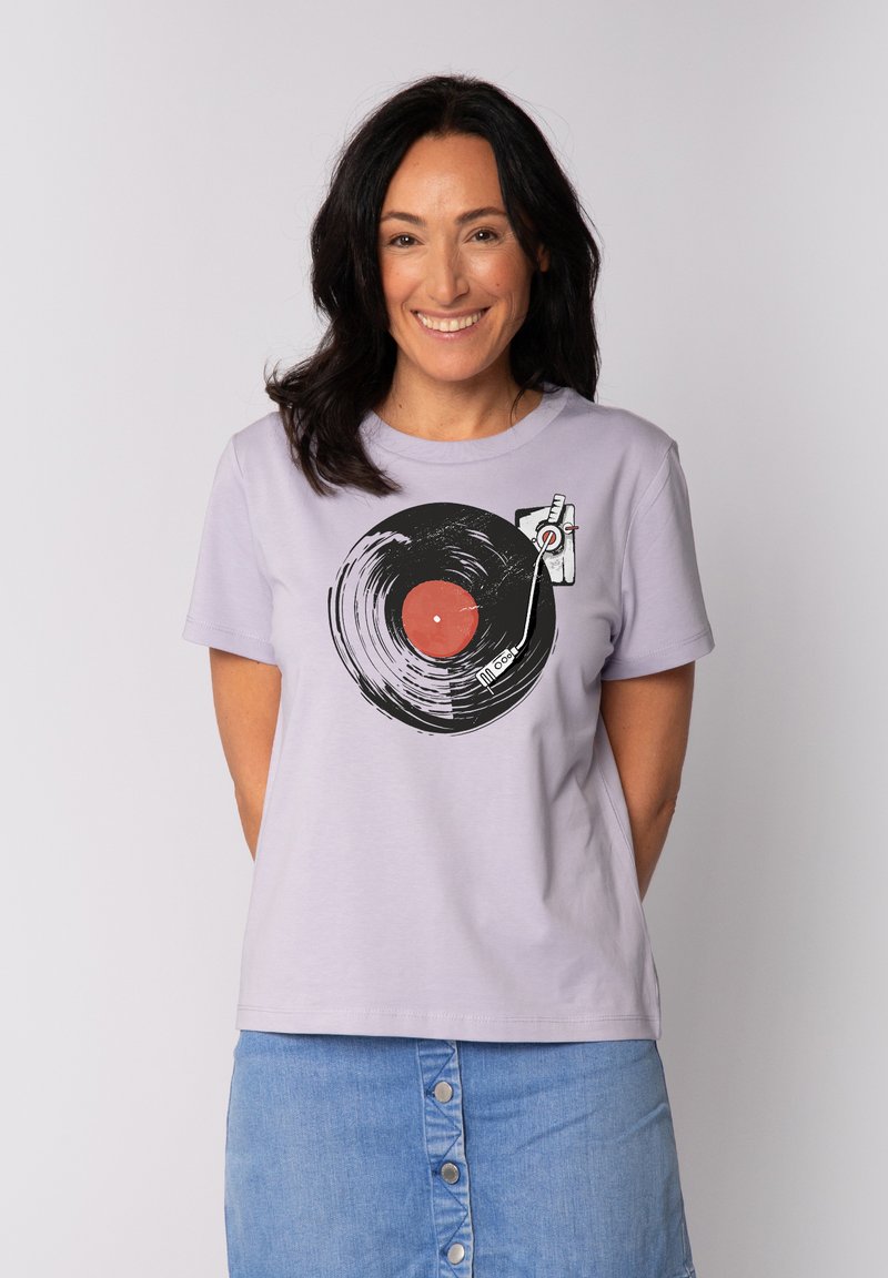 T-shirt lavande présentant un graphique d'un disque vinyle noir avec un centre rouge et des détails de platine. Tissu en coton doux, coupe décontractée.