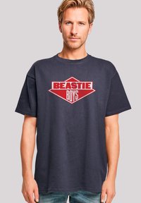 Navy t-shirt with short sleeves, featuring a bold red diamond logo that says "BEASTIE BOYS" in white and red typography.