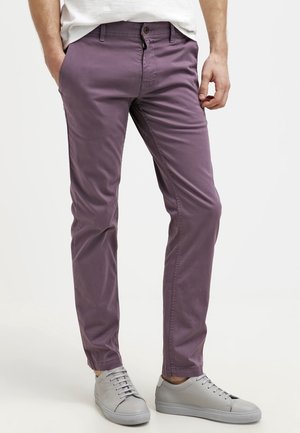 Lila Baumwoll-Chinos mit schmaler Passform, ausgestattet mit Fronttaschen und einem Knopfverschluss. Kombiniert mit grauen Sneakers. Glatte Textur.