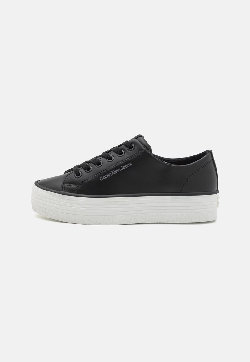 Must musta sneakerid valge kummist tallaga, sujuva tekstuuriga, ümarate varvaste ja paeltega. Nähtav "Calvin Klein Jeans" logo.