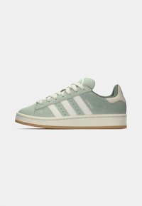 Green suede sneaker with white stripes, flat lace-up design, and a gum rubber sole. Features a padded collar and logo accents.