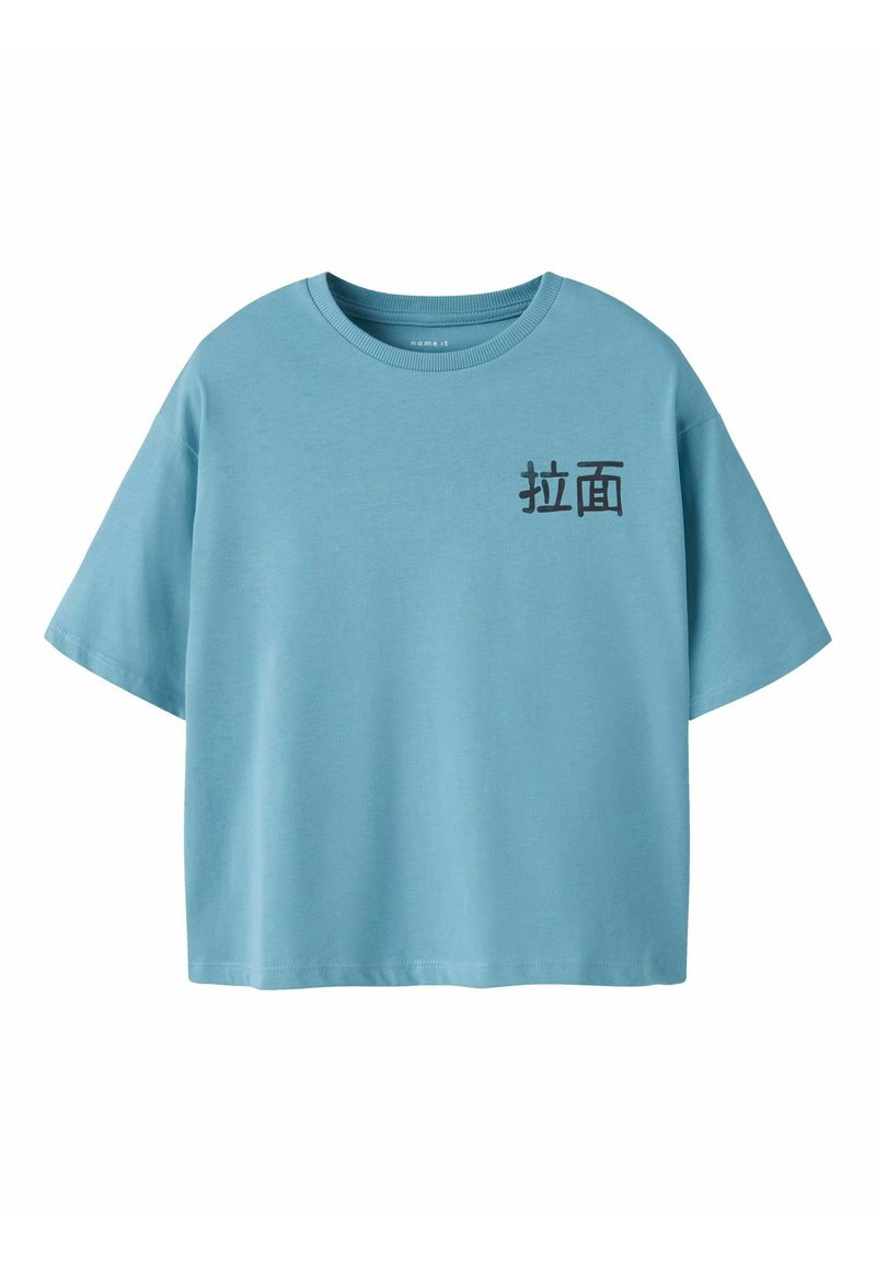 T-shirt en coton bleu clair à manches courtes et col rond. Présente un texte noir dans une police stylisée sur le côté gauche.