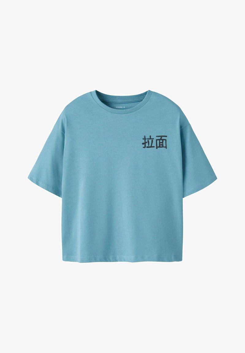 T-shirt en coton bleu clair à manches courtes et col rond. Présente un texte noir dans une police stylisée sur le côté gauche.