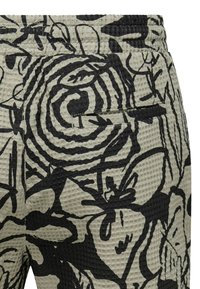 Diseño floral negro sobre tela texturizada de color gris claro. Presenta un patrón de rayas onduladas y está diseñado con un bolsillo visible en la parte posterior.