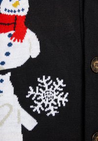 Svart stickad tröja med en vit snögubbe som har en röd halsduk, blå knappar och en vit snöflingedesign bredvid.