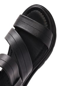 Black leather sandal featuring three wide straps, cushioned footbed, and a textured sole for comfort and grip.