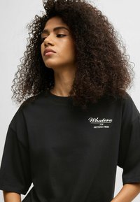Black cotton t-shirt with short, wide sleeves. Features white text that reads “Whatever I’m GETTING FRIES” in a bold, simple font.