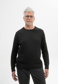 Zwarte gebreide trui met een ronde hals, geribbelde manchetten en zoom. Draag het met donkere broek, met een gladde textuur en een strakke pasvorm.