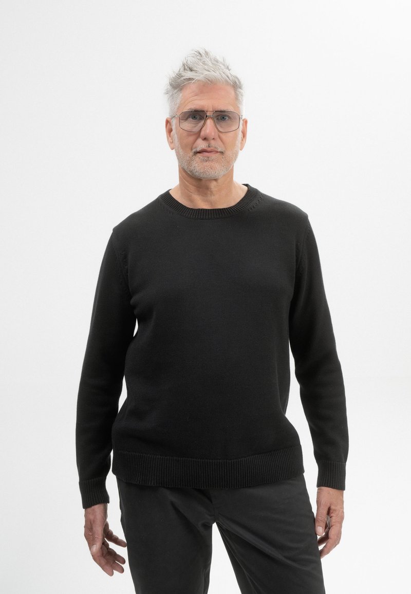 Zwarte gebreide trui met een ronde hals, geribbelde manchetten en zoom. Draag het met donkere broek, met een gladde textuur en een strakke pasvorm.
