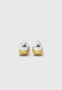 White and yellow athletic cleats featuring a smooth design, textured material, and three black stripes logo on the heel.