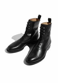 Botas de cuero negras hasta el tobillo con un acabado pulido, que cuentan con punta redonda, cordones en la parte delantera y acentos metálicos en los lados.