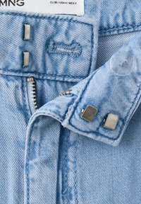 Ceinture de jean en denim bleu clair avec des crochets métalliques, fermeture éclair partiellement visible, bouton en plastique transparent et étiquette de taille (UE 36, USA 4).