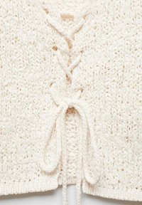 Haut au crochet en crème, présentant un col en V et une fermeture à lacets nouée en nœud. Motif en maille ouverte texturée avec une coupe ample.