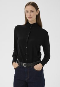 Fekete, hosszú ujjú, gombos ing magas gallérral, sima anyagból, gombsorral és testhezálló szabással.