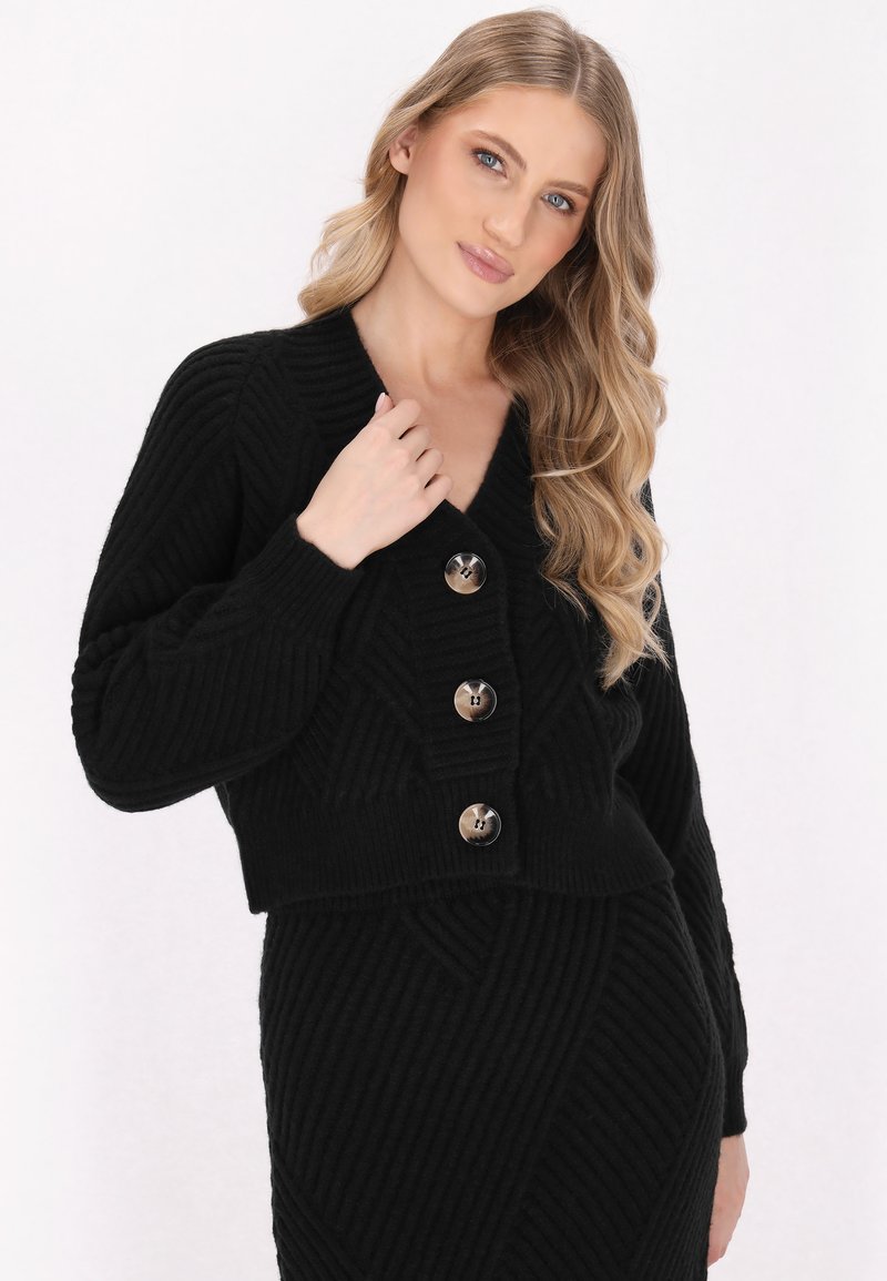 Schwarze, kurz geschnittene Strickjacke mit V-Ausschnitt, geripptem Muster und drei großen, runden silbernen Knöpfen auf der Vorderseite.