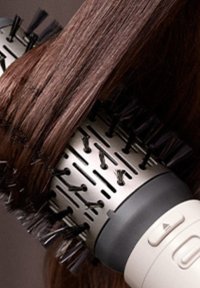 Ronde haarstylingborstel met een metalen cilinder, zwarte plastic haren en een witte handgreep met een knop voor controle. Bruine haarstrengen omwonden.