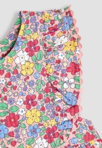 Tejido con estampado floral en rosa, que presenta flores en azul, rojo, amarillo y blanco. Bordes con volantes en el escote y las costuras.