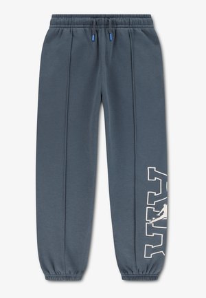 Pantalon jogger bleu foncé avec une ceinture élastique, des cordons bleus, des bas de jambe élastiques et de grandes lettres blanches en contour sur le bas de la jambe gauche.