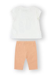 Blusa blanca de manga corta con detalles de encaje y pantalones naranjas. La blusa tiene un escote redondo y una tela ligeramente texturizada.