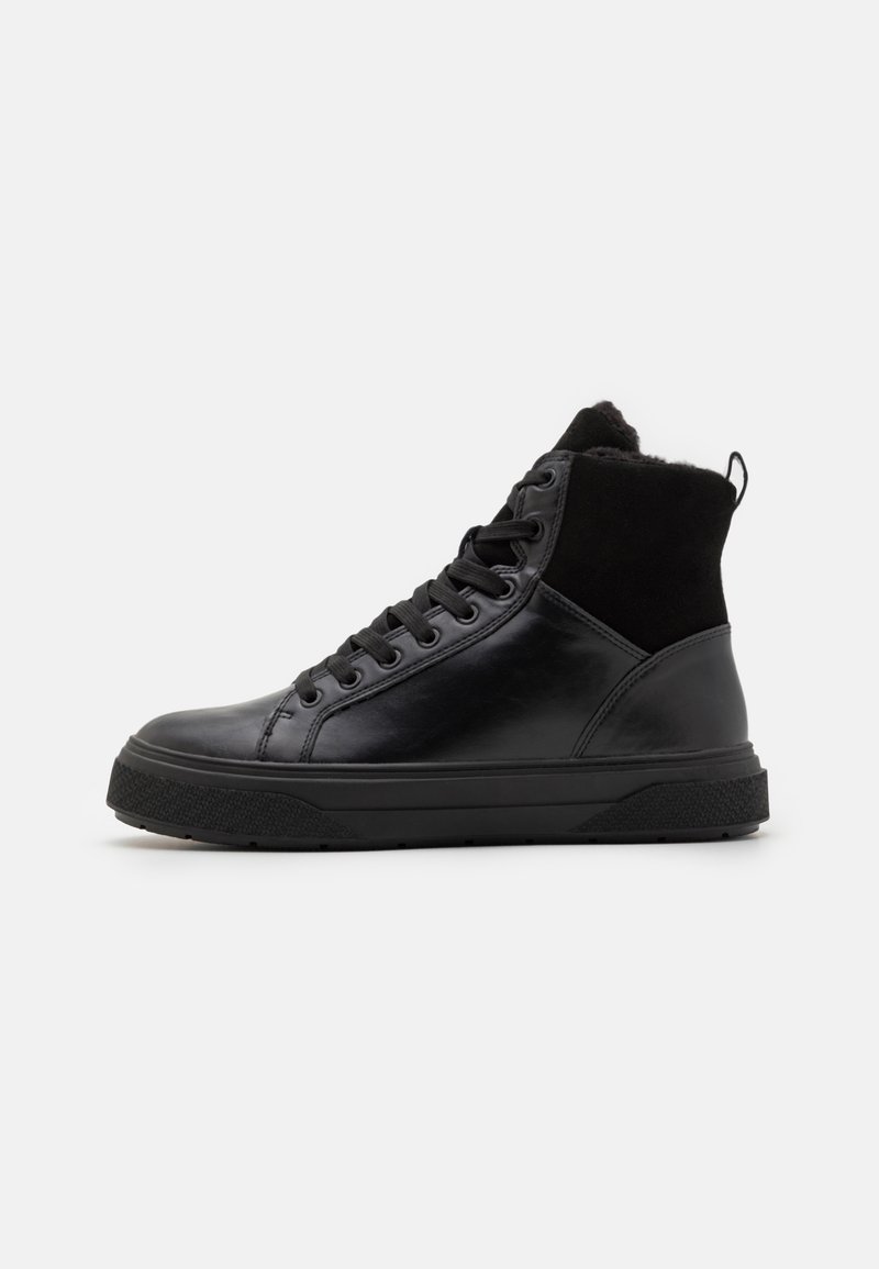 Adidași negri tip high-top cu partea superioară din piele netedă, accente din piele de căprioară, talpă din cauciuc texturat și șireturi rotunde. O bucată de prindere este la călcâi.