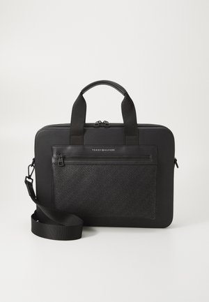Black rectangular briefcase with dual handles, detachable shoulder strap, front zip pocket with embossed pattern, and Tommy Hilfiger logo.
