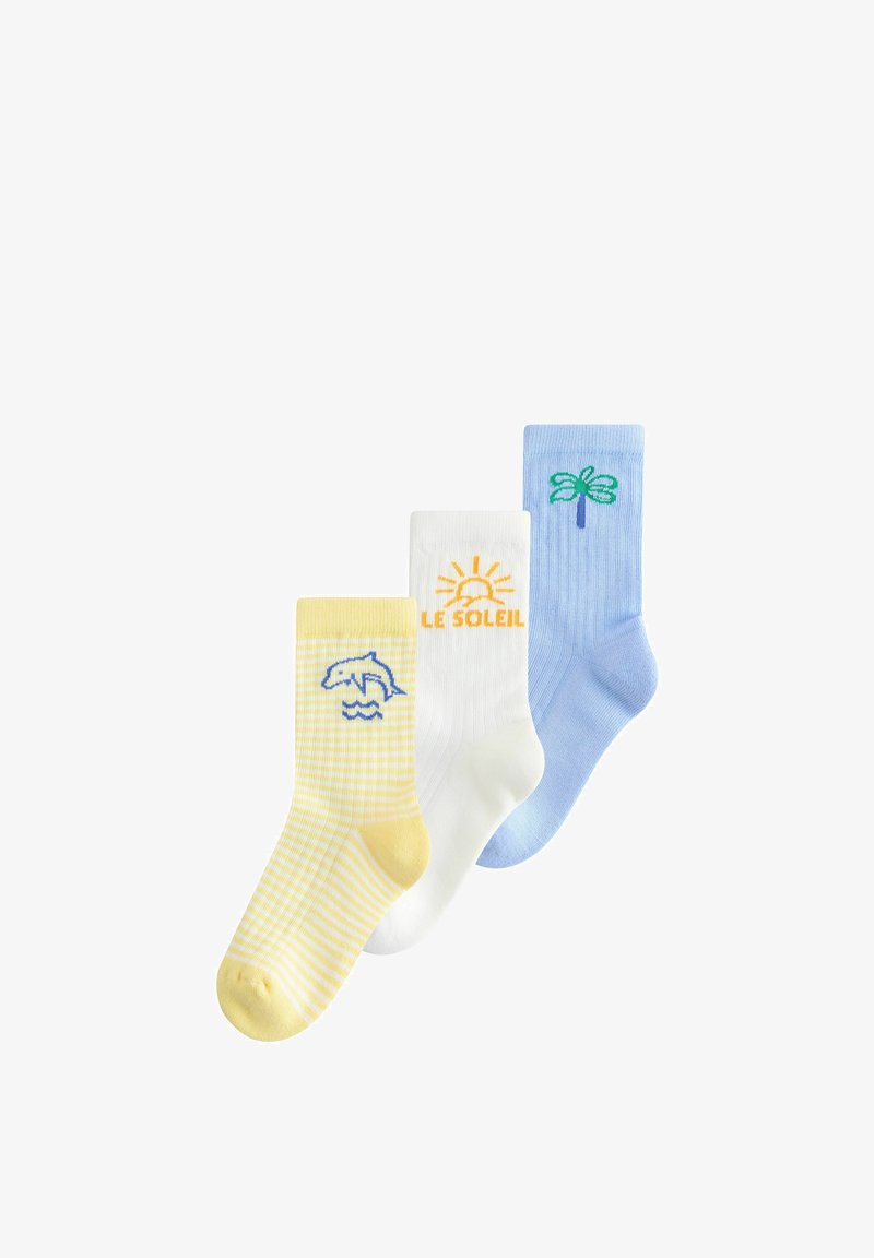 Trois chaussettes colorées avec des motifs estivaux : dauphin jaune sur des vagues, soleil blanc avec le texte "LE SOLEIL", et palmier bleu.