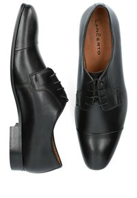 Chaussures habillées en cuir noir avec une texture lisse, munies d'un bout arrondi, d'un laçage et d'un talon en bois. Logo de la marque visible à l'intérieur.