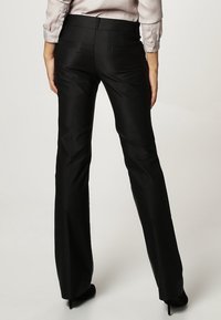 Svarta utsvängda byxor i ett slätt tyg, med midjehöjd i midjan, två bakfickor och en skräddarsydd passform som går ner till ankeln.