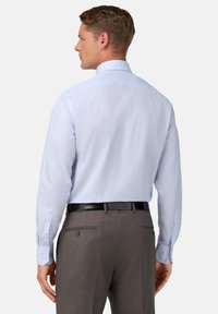 Lichtblauw overhemd met lange mouwen, knopenmanchetten en een gladde textuur, gecombineerd met grijze broek met achterzakken en een knoopdetail.