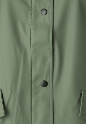 Veste de pluie vert clair avec une texture lisse, dotée de boutons-pression noirs et de deux poches latérales. Design simple et fonctionnel.