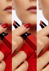 Red lipstick in a square red casing, with a black twist mechanism. Smooth texture, glossy finish, and visibly rich red shade.