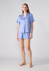 Satin blå kort pyjamas-sett som inneholder en krage med knapper skjorte med vertikale striper og matchende shorts. Glatt tekstur, uformelt design.