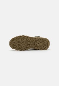 Semelle en caoutchouc marron pour randonnée avec de profondes rainures et motifs de traction. Détails texturés et talon renforcé pour plus de durabilité.