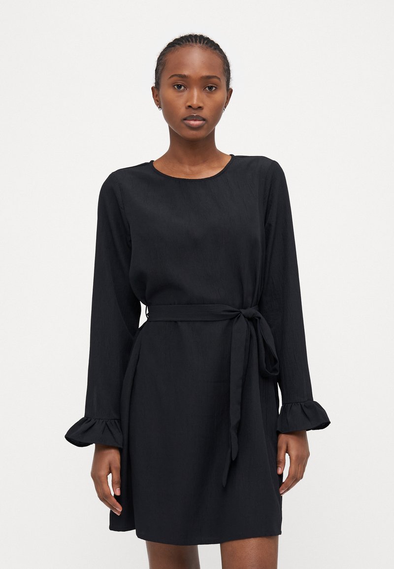 Μαύρο φόρεμα με μακριά μανίκια και ριγωτές μανσέτες, διαθέτοντας ζώνη στη μέση που δένει. Λείος υφασμάτινος χαρακτήρας με κλασικό στρογγυλό λαιμό.